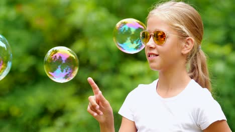 Niña-jugando-con-pompas-de-jabón-al-aire-libre.-Cámara-lenta.