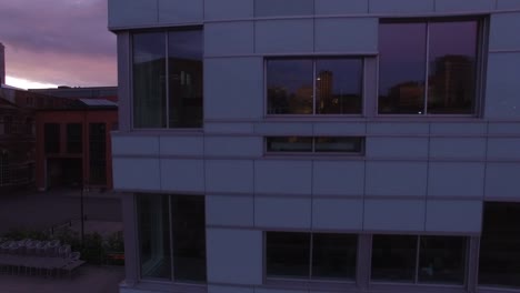 Establishing-shot:-Flying-up-in-front-of-office-building-exterior-facade.-Close-up-aerial-shot-of-office-buildings-wall-and-windows