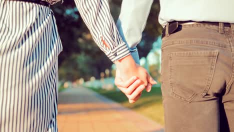 Young-loving-couple-holding-hands-walking-along-the-summer-park