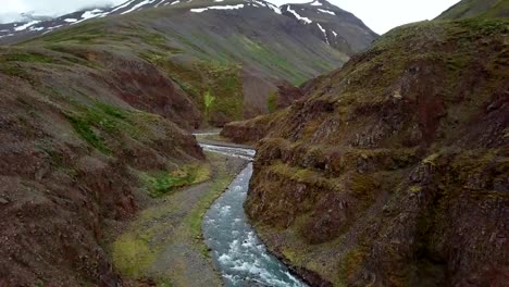 Stunning-drone-view-of-woman-standing-arms-outstretched-on-top-of-canyon-in-Iceland