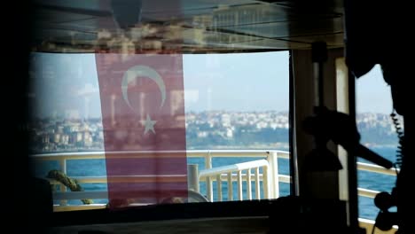 Watching-view-through-Turkish-flag-on-board-of-tourist-vessel,-public-transport