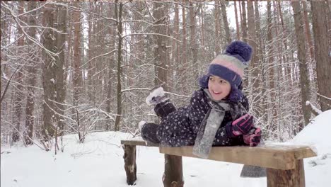 Chica-acostado-en-un-banco-de-madera-en-invierno