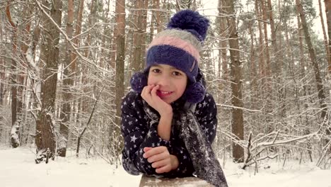 Girl-lying-on-a-log-on-the-background-of-the-winter-forest