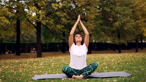 Gut-aussehende-Mädchen-setzt-Hände-in-Namaste-sitzen-im-Lotussitz-und-Breating-entspannen-ihren-Körper-und-Geist.-Meditation,-Hatha-Yoga-und-Menschen-Konzept.