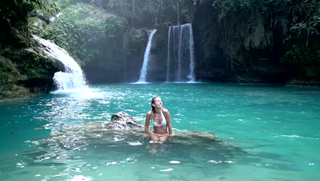 Young-woman-contemplating-a-beautiful-waterfall-on-the-Cebu-Island-in-the-Philippines.-People-travel-nature-loving-concept.-One-person-only-enjoying-outdoors-and-tranquillity-in-a-peaceful-environment
