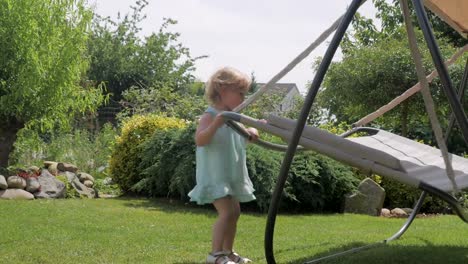 Niedlichen-Kleinkind-Mädchen-in-der-Nähe-von-Hängematte-im-Garten