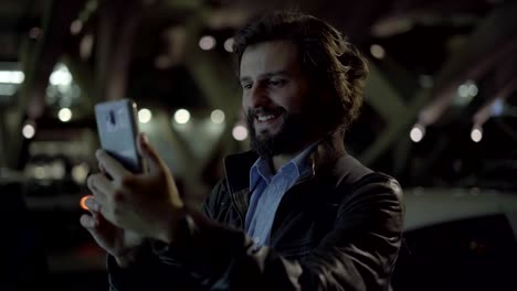 Young-Caucasian-man-having-video-call-on-smartphone-at-night