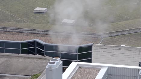 Vapor-y-humo-braman-de-una-chimenea-en-la-cima-de-un-edificio-de-departamentos