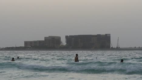 Por-la-noche,-los-Emiratos-Árabes-Unidos-swimers-Dubai-Palma-Hotel-con-una-vista-de-la-construcción-4-K