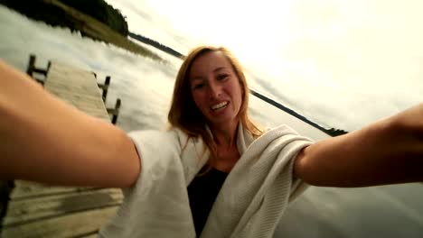 Young-woman-on-wooden-wharf-above-lake,-takes-selfie-portrait