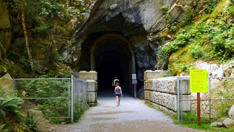 Woman-Walks-into-Train-Tunnel,-Gravel-Path,-Othello-Tunnels,-Hope-BC-Canada