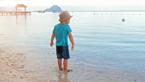 Netter-Junge-wirft-Kieselsteine-ins-Meer-Inzeitbewegung