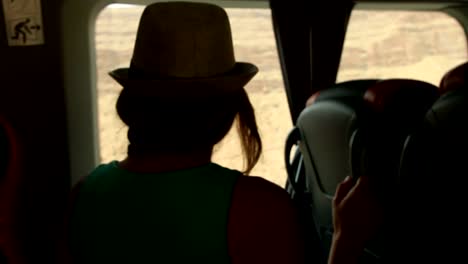 Young-woman-looking-trough-the-window-and-playing-with-hands-sitting-on-backseats-in-bus-during-road-trip