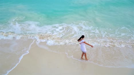 Young-beautiful-woman-on-tropical-seashore.-Above-view-of-happy-girl-in-beautiful-dress-on-white-beach