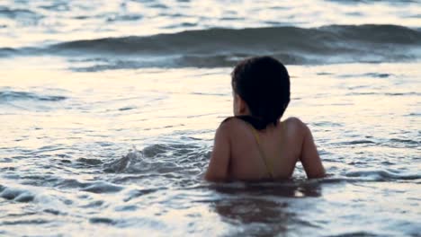 Niña-jugando-en-la-playa-en-el-agua-durante-la-hora-del-atardecer