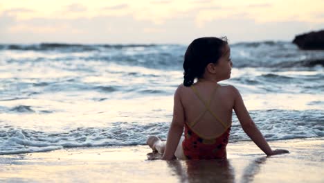 Kleine-Mädchen-spielen-am-Strand-im-Wasser-während-Sonnenuntergang-Stunde