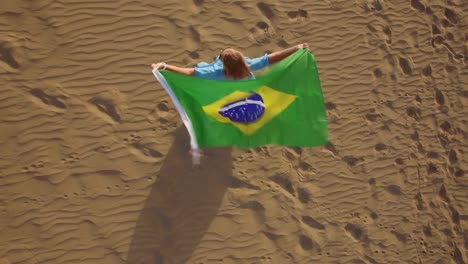 Woman-with-Brazilian-flag-waving-in-the-wind,-aerial-view