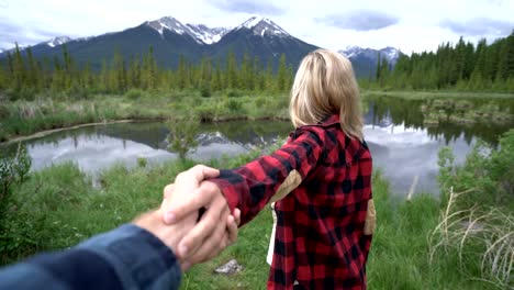 Young-woman-leading-man-to-mountain-lake