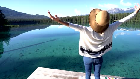 Woman-arms-outreached-by-alpine-lake-in-the-Canadians-rockies