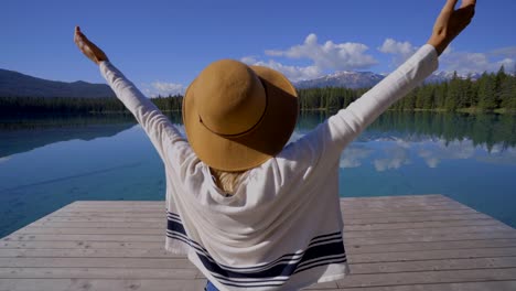 Woman-arms-outreached-by-alpine-lake-in-the-Canadians-rockies