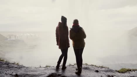 Back-view-of-two-happy-woman-standing-near-the-Gljufrabui-in-Iceland.-Traveling-female-exploring-the-famous-sights