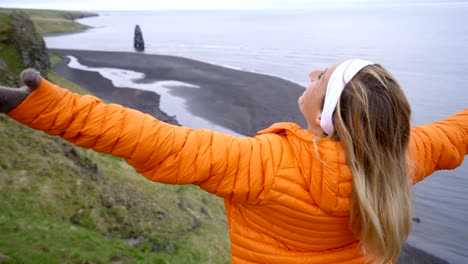 Young-woman-arms-outstretched-at-Hvitserkur-basalt-stack-along-the-eastern-shore-of-the-Vatnsnes-peninsula,-in-northwest-Iceland.-People-travel-lifestyles-concept