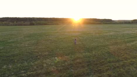 Nicht-erkennbare-Frau-zu-Fuß-auf-dem-Feld-bei-Sonnenuntergang-ausgestreckten-Armen.