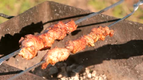 Appetitlich-saftiges-Eisbein-wird-am-Spieß-über-Holzkohle-Grill-gebraten.-Close-up-Fleischstücke.