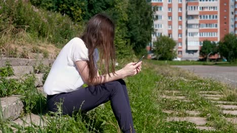 Frau-Typen-eine-Nachricht-am-Telefon-sitzen-im-Park.