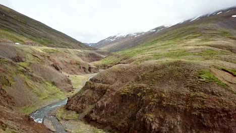 Stunning-drone-view-of-woman-standing-arms-outstretched-on-top-of-canyon-in-Iceland