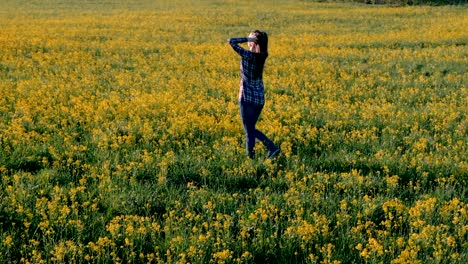Brünette-Frau-geht-auf-dem-Gebiet-der-gelben-Blüten.