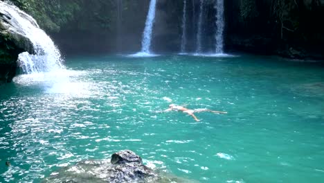 Young-woman-swimming-in-idyllic-waterfall-in-tropical-forest-located-in-the-Philippines-Islands.-People-travel-fun-enjoyment-vacations-concept