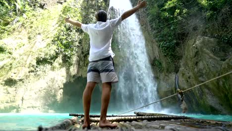 Junger-Mann-umarmt-schönen-Wasserfall-in-den-Philippinen