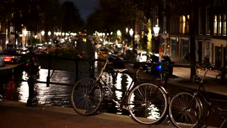 eine-Nachtaufnahme-von-einem-Fahrrad-angekettet-an-einer-Brücke-über-einen-Kanal-in-amsterdam