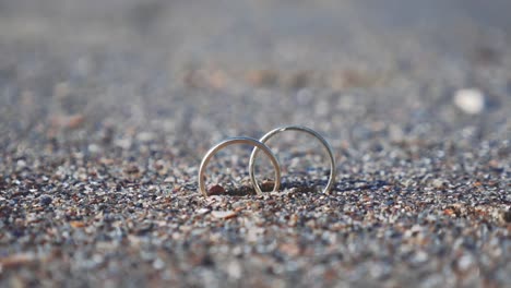 Par-de-anillos-de-boda-enterrado-en-arena