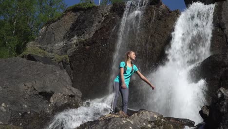 Die-Mädchen-Tänze-in-der-Nähe-des-Wasserfalls