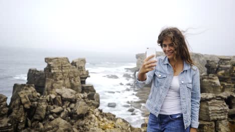 Junge-Frau,-die-die-Selfie-auf-Smartphone-am-Stein-Ufer-in-der-Nähe-von-Wasser