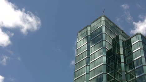 Blue-green-office-tower.-Time-lapse-cloud-reflections.