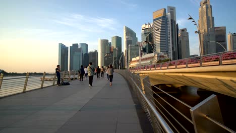 Passanten-in-Marina-Bay,-Singapur-mit-Wolkenkratzern-als-Hintergrund