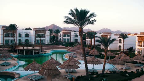 Hotel-Resort-with-Blue-Pool,-Palm-Trees-and-Sunbeds-in-Egypt