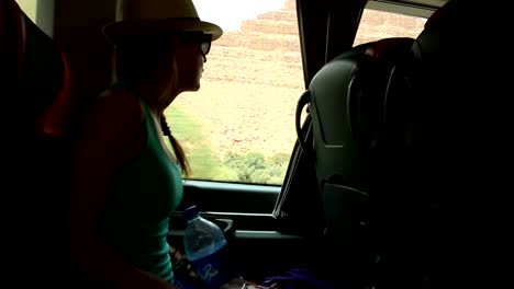 Young-woman-looking-trough-the-window-and-playing-with-hands-sitting-on-backseats-in-bus-during-road-trip