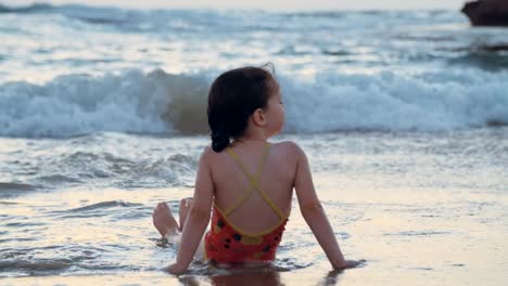 Niña-jugando-en-la-playa-en-el-agua-durante-la-hora-del-atardecer