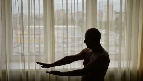 Silhouette-der-Mann-tut-Tai-Chi-zu-Hause-vor-Fenster.-Asiatische-Vormittagstraining.-Im-Haus-gesperrt.