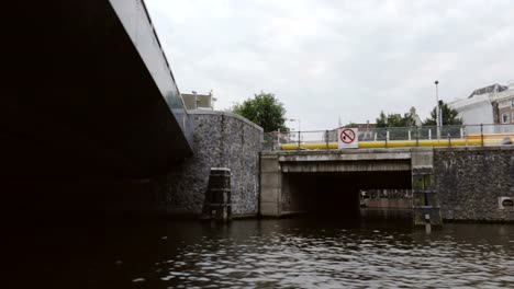 Filmación-de-las-calles-de-Amsterdam-y-las-aguas-del-Canal-mientras-se-desliza-debajo-de-un-puente