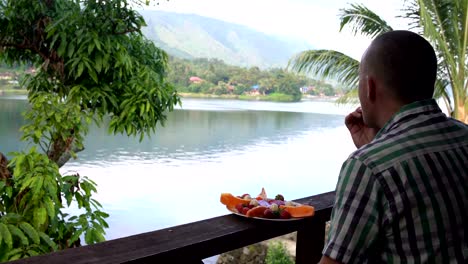 A-man-eats-strawberries-and-looks-at-the-lake-and-mountains