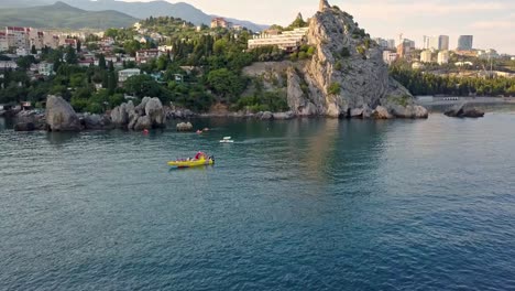 aerial-drone-flying-shot-of-cruise-touristic-catamaran-passing-by-the-sea-rocky-coast