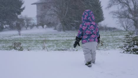 Kleinkind-zu-Fuß-in-einem-verschneiten-Hinterhof