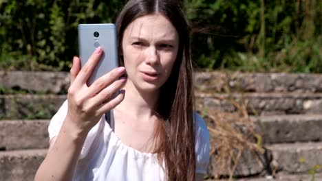 Young-woman-calling-on-the-phone-on-video-chat,-talking-and-smiling.