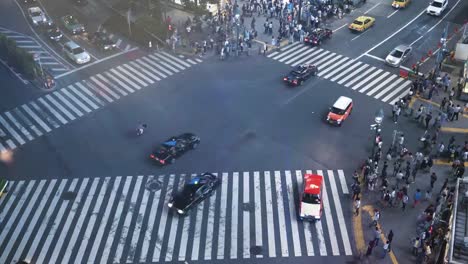 High-Angle-Zeit-verfallen-Schuss-von-den-berühmten-Shibuya-Pedestrian-Scramble-Zebrastreifen-mit-Massen-von-Menschen-überqueren-und-Verkehr.-Abends-in-der-Großstadt.