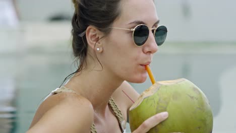 Mujer-en-gafas-de-sol-bebiendo-agua-de-coco